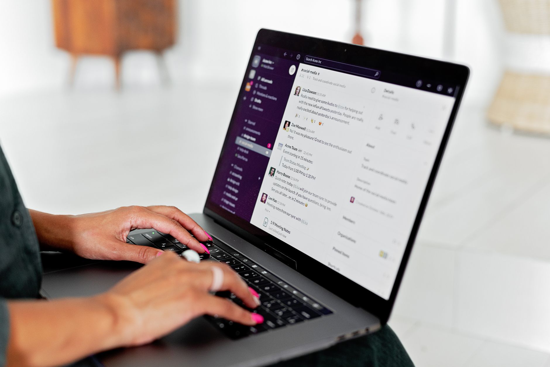 A person at a desk types on a laptop with an AI chat interface open beside a notebook and plant.