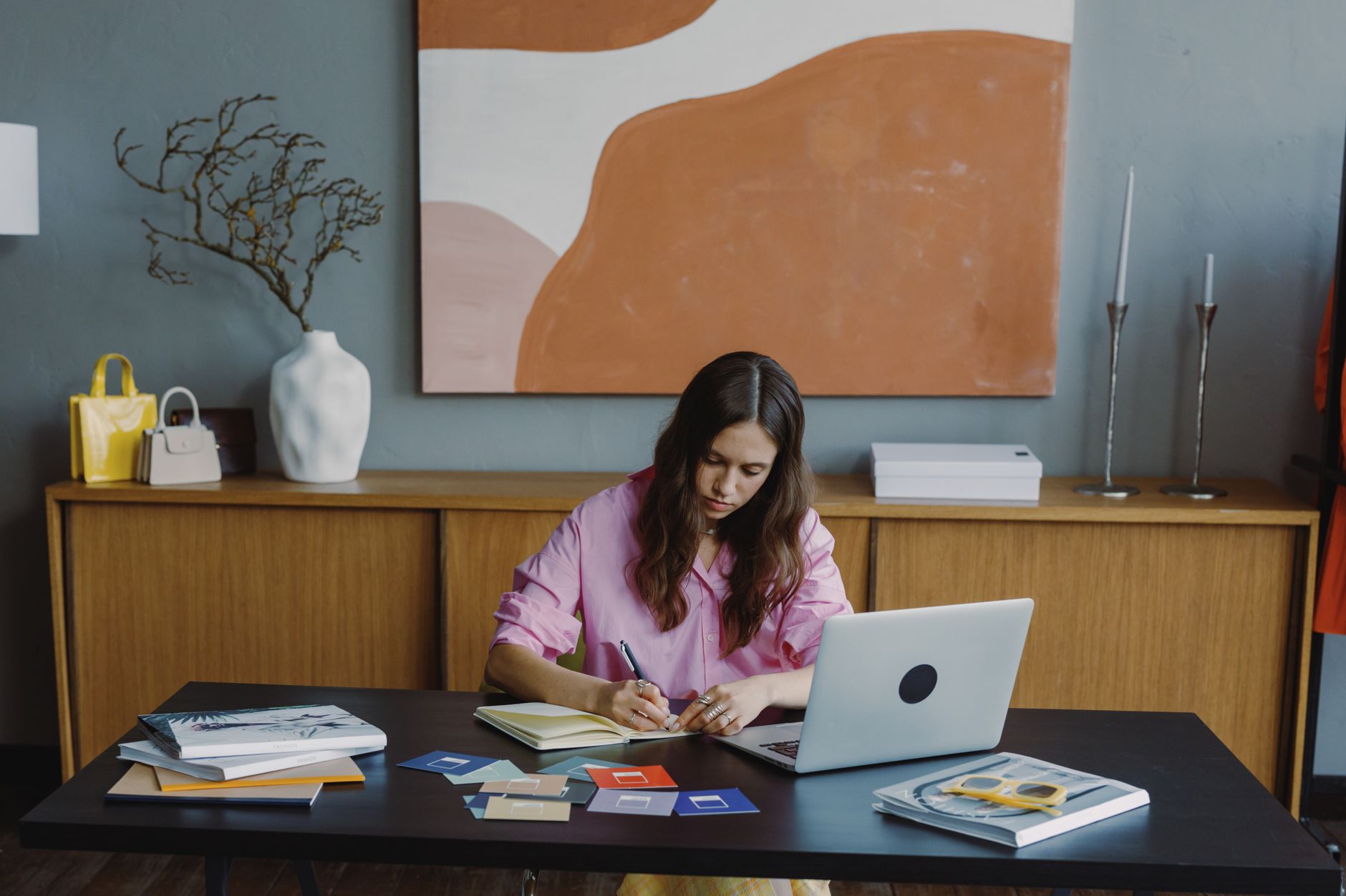 a woman designing a social media template on a laptop with color swatches nearby